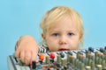 A little girl tries to move the fender slider to increase the volume on a music mixing console Royalty Free Stock Photo