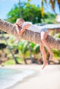 Adorable little girl at tropical beach sitting on palm tree during summer vacation Royalty Free Stock Photo