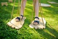 Little girl trying to walk on giant wooden feet in the park. Child playing funny outdoor game on sunny summer day. Family leisure