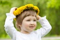 Little girl trying on yellow chaplet made of dandelions