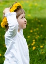 Little girl trying on yellow chaplet made of dandelions Royalty Free Stock Photo