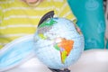 A little girl of two years old is sitting in a baby chair and is holding a medical mask in her hands. Child with a globe, globe Royalty Free Stock Photo