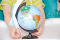 A little girl of two years old is sitting in a baby chair and is holding a medical mask in her hands. Child with a globe, globe Royalty Free Stock Photo