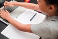 Little girl typing on the laptop. Detail of schoolchild taking notes and using the laptop on the black desk