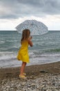 Little girl with umbrella on beach in bad weather Royalty Free Stock Photo