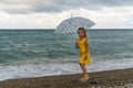 Little girl with umbrella on beach in bad weather Royalty Free Stock Photo