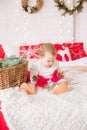 A little girl under one year old in an airy dress on a large bed in a room decorated for Christmas Royalty Free Stock Photo