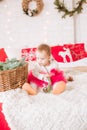 A little girl under one year old in an airy dress on a large bed in a room decorated for Christmas Royalty Free Stock Photo