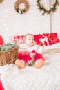 A little girl under one year old in an airy dress on a large bed in a room decorated for Christmas Royalty Free Stock Photo