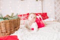 A little girl under one year old in an airy dress on a large bed in a room decorated for Christmas Royalty Free Stock Photo