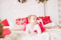 A little girl under one year old in an airy dress on a large bed in a room decorated for Christmas Royalty Free Stock Photo