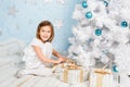 Little girl unties the ribbon on a Christmas present