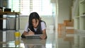 A little girl is using a computer tablet and stylus pen while lying on the living room ground floor Royalty Free Stock Photo