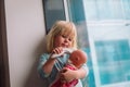 Little girl using electronic thermometer for doll with mask at home. Pandemic COVID-19 Royalty Free Stock Photo