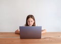 Little girl using laptop at home at wooden table. Education, online learning, home learning, distance learning. Front view Royalty Free Stock Photo