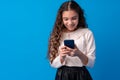 Little girl using mobile phone.against blue background Royalty Free Stock Photo