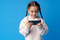 Little girl using mobile phone.against blue background Royalty Free Stock Photo