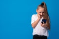 Little girl using mobile phone.against blue background Royalty Free Stock Photo