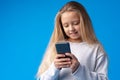 Little girl using mobile phone.against blue background Royalty Free Stock Photo