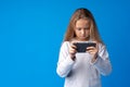 Little girl using mobile phone.against blue background Royalty Free Stock Photo