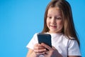 Little girl using mobile phone.against blue background Royalty Free Stock Photo