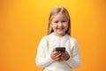 Little girl using mobile phone.against yellow background Royalty Free Stock Photo