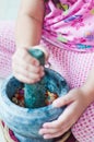 A little girl is using the mortar and pestle or lesung batu in Malay.