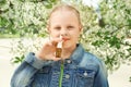 Little girl using nasal drops near blooming tree. Allergy concept Royalty Free Stock Photo