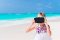 Little girl using VR virtual reality goggles. Adorable kid look into the virtual glasses on white beach Royalty Free Stock Photo