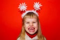 The little girl is very emotionally angry and expresses dissatisfaction. Red background. Portrait. Christmas decoration Royalty Free Stock Photo