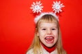 The little girl is very emotionally angry and expresses dissatisfaction. Red background. Portrait. Christmas decoration Royalty Free Stock Photo