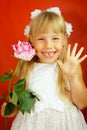 Little girl is very happy with the gift of flower. Pink rose in the hands of a girl. Birthday, holiday. Red background Royalty Free Stock Photo