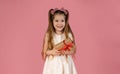 The little girl is very happy to have received an unexpected gift, and she is pictured enjoying this gift on a pink Royalty Free Stock Photo