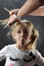 Little girl is very surprised when combing hair with female hands Royalty Free Stock Photo