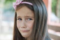 The little girl is very upset and sad, sits on a bench in the park summer