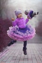 Little girl in the violet dress dancing with a toy cat Royalty Free Stock Photo