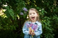 Little girl with waffle ice cream cone filled with lilac flowers in her hands Royalty Free Stock Photo