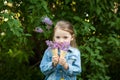 Little girl with waffle ice cream cone filled with lilac flowers in her hands Royalty Free Stock Photo