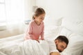Little girl waking her sleeping father up in bed Royalty Free Stock Photo