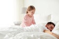 Little girl waking her sleeping father up in bed Royalty Free Stock Photo