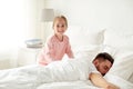 Little girl waking her sleeping father up in bed Royalty Free Stock Photo