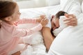 Little girl waking her sleeping father up in bed Royalty Free Stock Photo