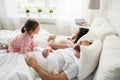 Little girl waking her sleeping parents up in bed Royalty Free Stock Photo