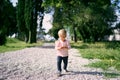 Little girl walking along a pebble path in a green park Royalty Free Stock Photo