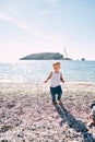 Little girl walking barefoot on a pebbly beach Royalty Free Stock Photo