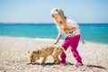 Little girl walking on the beach with a puppy terrier