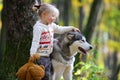 Little girl walking with dog in autumn forest. Royalty Free Stock Photo