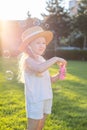 A little girl is walking in the park blowing up soap bubbles. Have fun on a sunny summer day Royalty Free Stock Photo