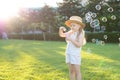 A little girl is walking in the park blowing up soap bubbles. Have fun on a sunny summer day Royalty Free Stock Photo