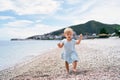 Little girl walking on a pebble beach with a pebble in her hand Royalty Free Stock Photo